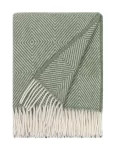 A wool blanket featuring a green and white diamond twill pattern, complete with white fringe, made by weaving mill Barker Textiles.