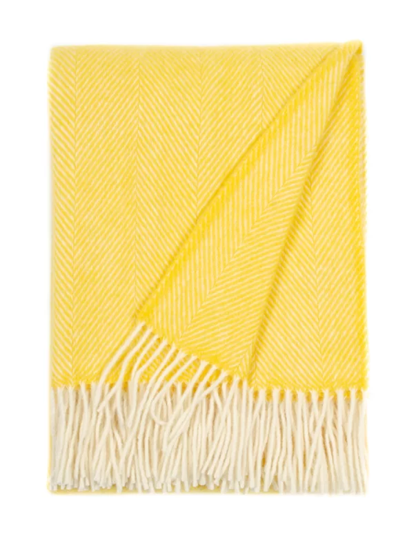 A wool blanket showcasing a chevron pattern in a melon orange shade, complete with white fringe edges, made by weaving mill Barker Textiles.