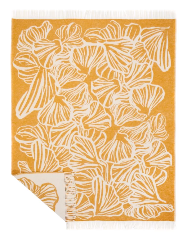 A wool blanket with a detailed leafy pattern in white against a mustard yellow background, finished with a fringe, made by weaving mill Barker Textiles.