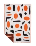 A wool blanket with a bold pop art design featuring large orange dots and black abstract shapes on a white background, bordered with fringe, made by weaving mill Barker Textiles.