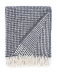 A wool blanket with a textured waffle pattern in gray and white, featuring white fringes, made by weaving mill Barker Textiles.