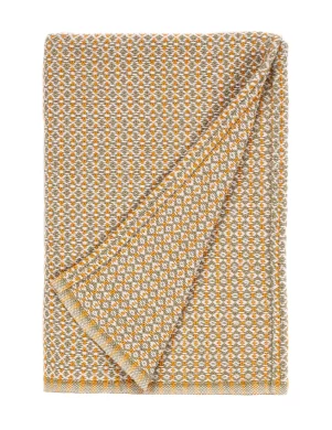 A baby blanket with a complex geometric pattern in beige, orange, and white, folded to show the reverse side made by weaving mill Barker Textiles.