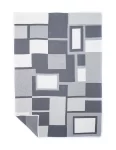 Gray blanket featuring white and dark gray geometric block patterns, neatly folded with one corner flipped to show the reverse side, made by weaving mill Barker Textiles.