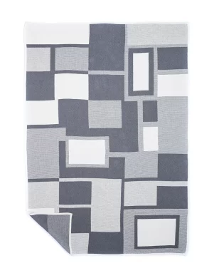 Gray blanket featuring white and dark gray geometric block patterns, neatly folded with one corner flipped to show the reverse side, made by weaving mill Barker Textiles.