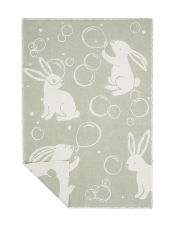 A soft, light green baby blanket featuring playful white rabbits blowing bubbles made by weaving mill Barker Textiles.