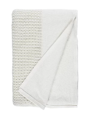 A white blanket with a folded corner, displaying a blue decorative stripe along one edge made by weaving mill Barker Textiles.