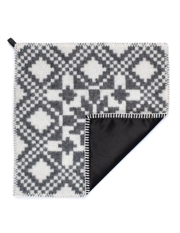 Sitting pad with a black and white folk pattern, featuring a black backing made by weaving mill Barker Textiles.