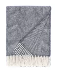 A recycled wool blanket with a chevron pattern in a grey shade, complete with white fringe edges, made by weaving mill Barker Textiles.