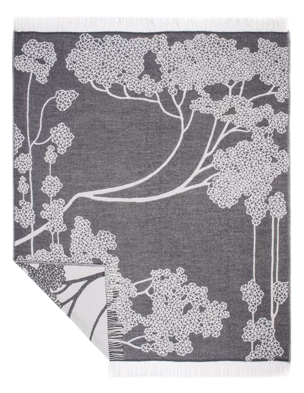 A dark gray wool blanket with a white floral tree design and fringed edges, crafted by Barker Textiles.