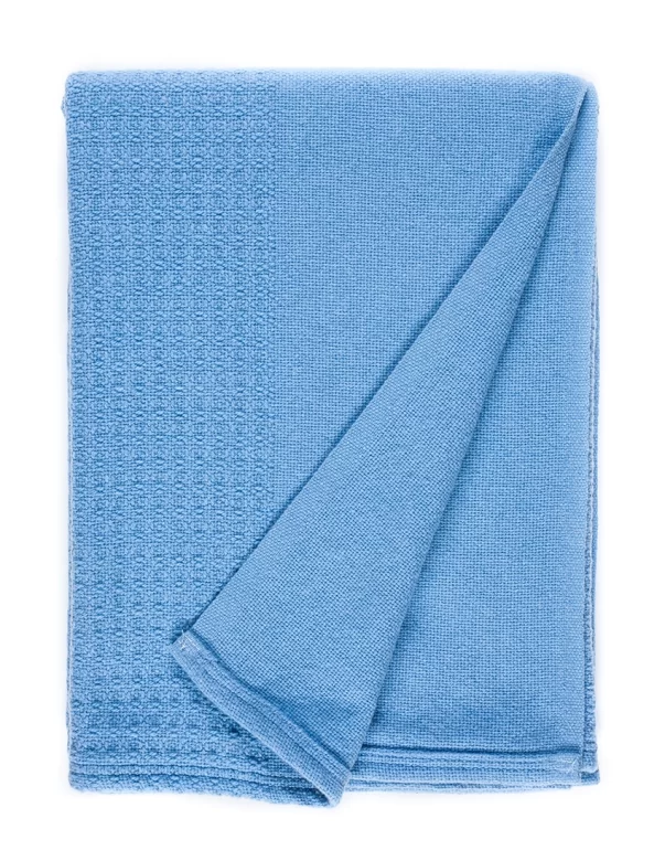 A white blanket with a folded corner, displaying a blue decorative stripe along one edge made by weaving mill Barker Textiles.